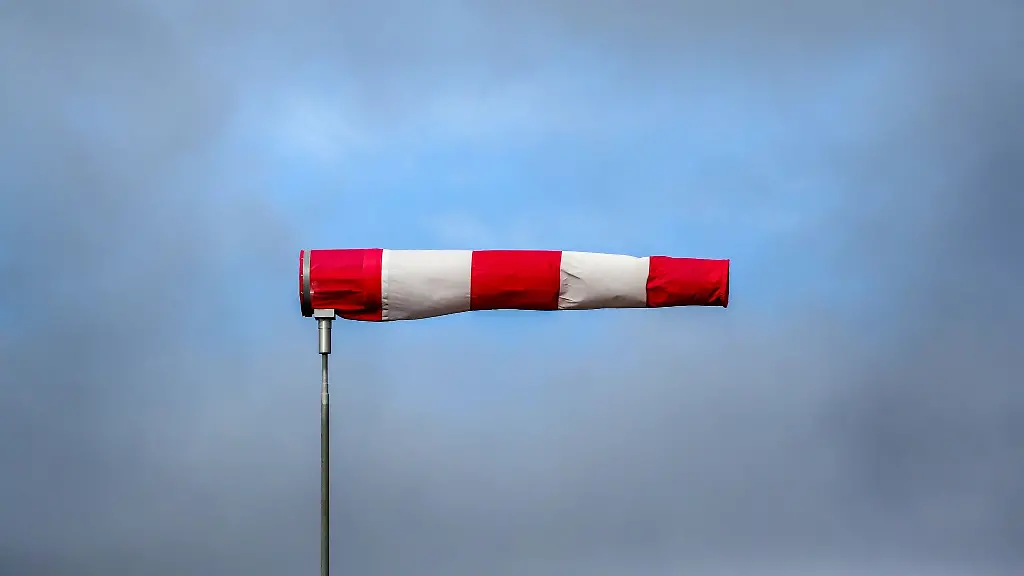 Hinter-einem-im-Sturm-stehenden-Windsack-hat-sich-eine-Wolkenluecke-gebildet