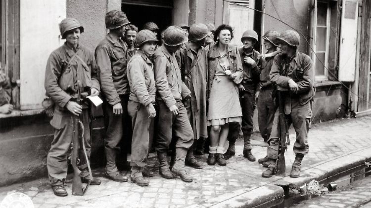 US-Soldaten mit einer Französin in einem Dorf in der Normandie im Juni 1944.