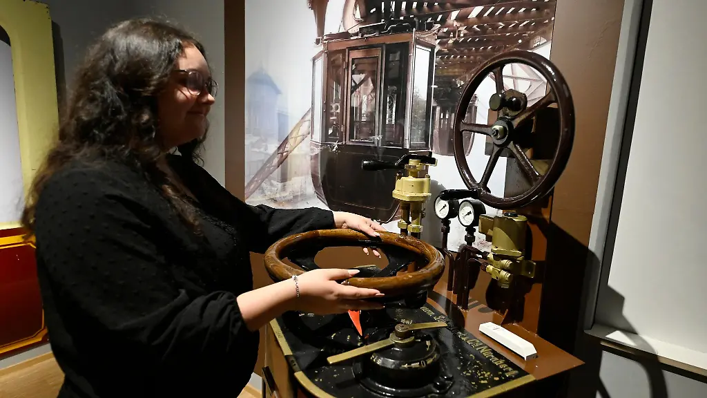 Eine-Frau-versucht-sich-an-einem-Fahrrad-der-Schwebebahn-in-den-Raeumlichkeiten-des-neuen-Museums-Schwebodrom