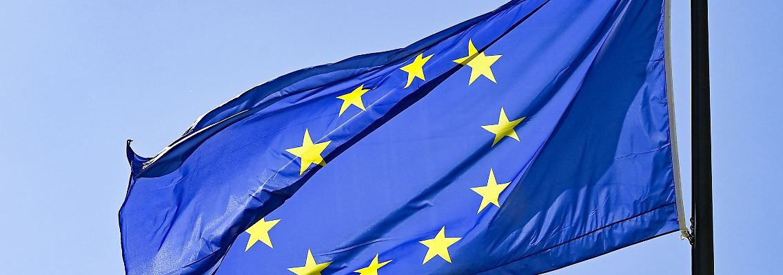Eine Europaflagge weht vor blauem Himmel.