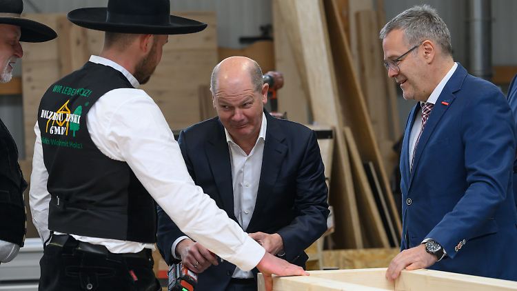 Handwerkspräsident Dittrich (r) assistiert Scholz beim Einsatz eines Akkuschraubers. 