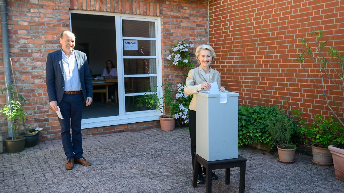 Ursula von der Leyen wirft neben ihrem Ehemann Heiko ihren Stimmzettel in eine Wahlurne.