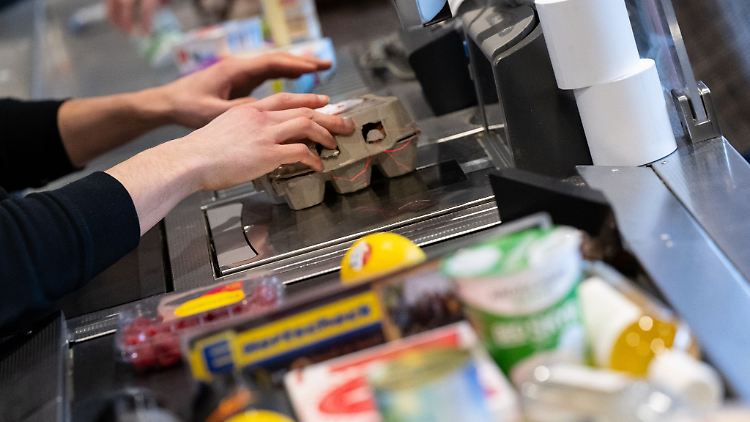 Ein Kassierer scannt in einem Supermarkt an der Kasse die Produkte.