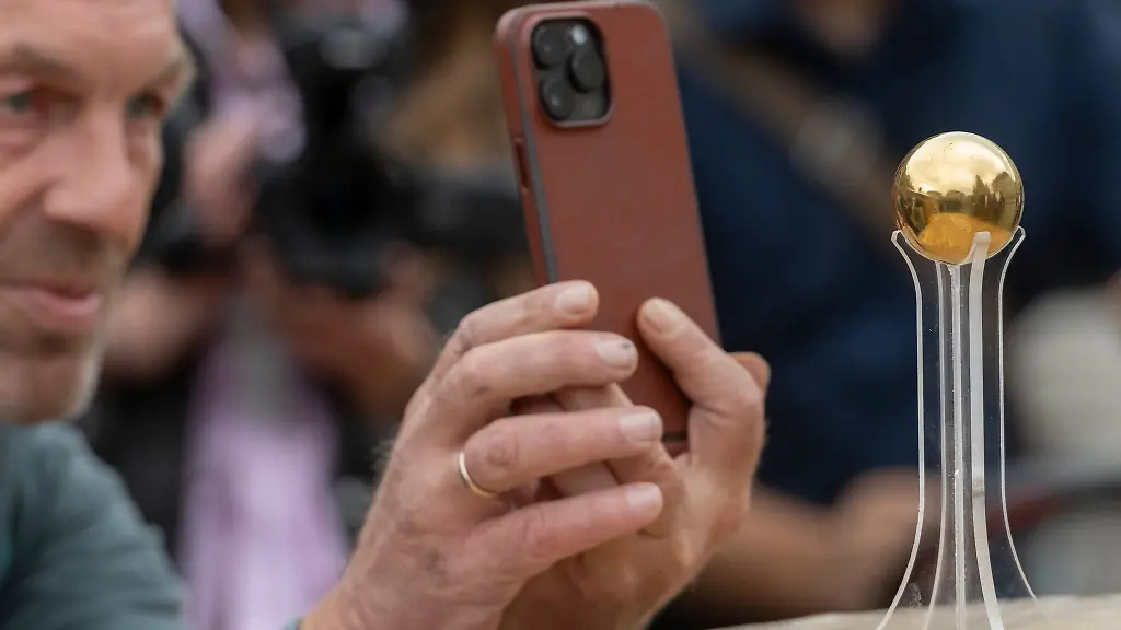 Ein-Mann-fotografiert-die-Goldene-Sphaere-des-Kuenstlers-Castello-nach-ihrer-Enthuellung-auf-dem-Neumark