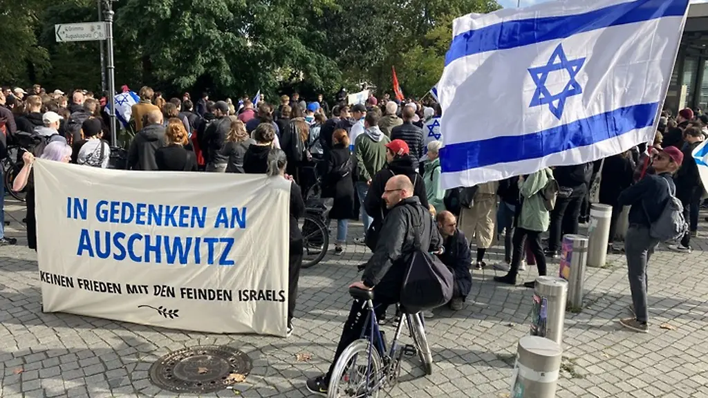 Eine-israelische-Fahne-und-ein-Transparent-tragen-Teilnehmer-einer-Kundgebung-in-Leipzig