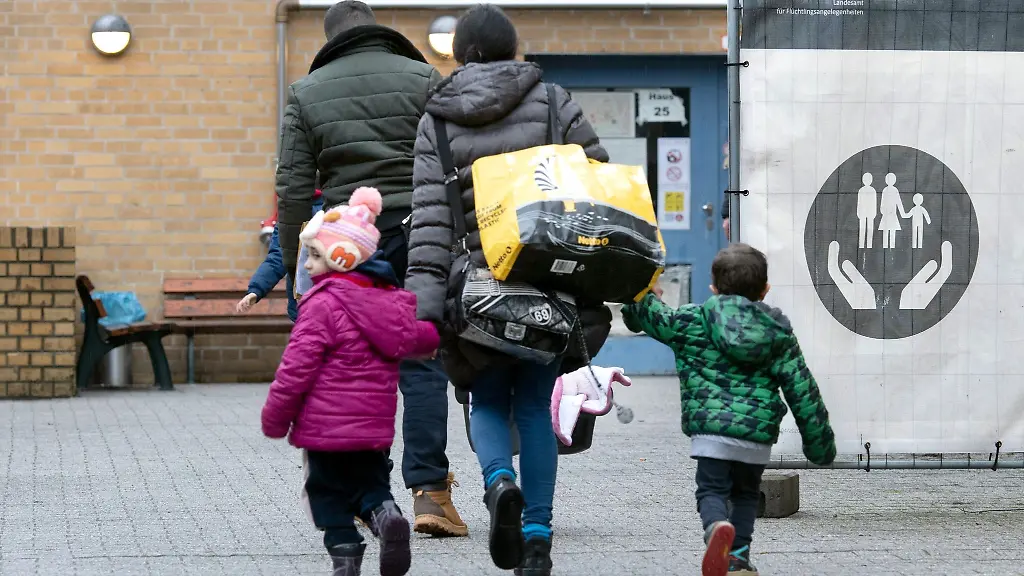 Eine-gefluechtete-Familie-geht-ueber-das-Gelaende-einer-Erstaufnahmeeinrichtung