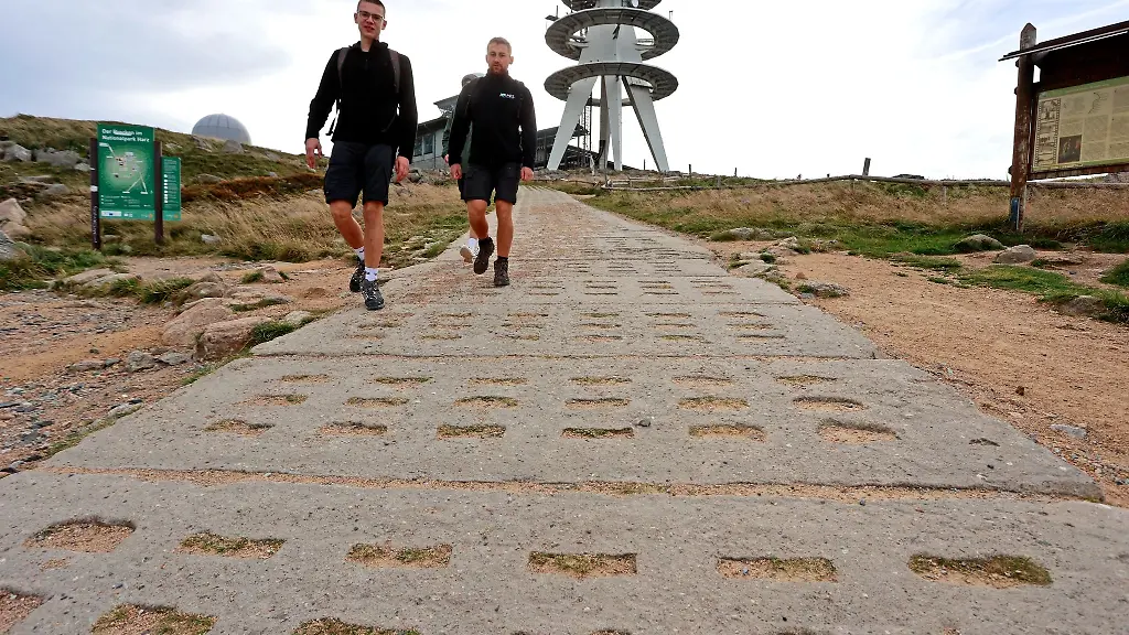 Wanderer-gehen-auf-dem-Brocken-im-Wind-auf-dem-Kolonnenweg-der-ehemaligen-Grenztruppen-der-Nationalen-Volksarmee-NVA