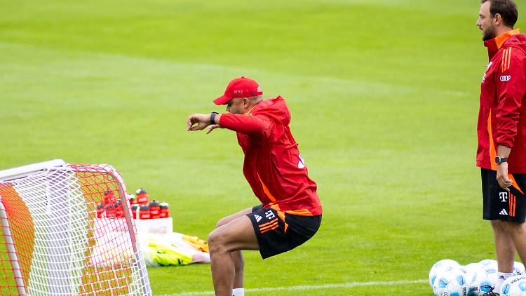 Vincent Kompany (m.) setzt sich auf einen Ball. Co-Trainer Rene Maric schaut zu.