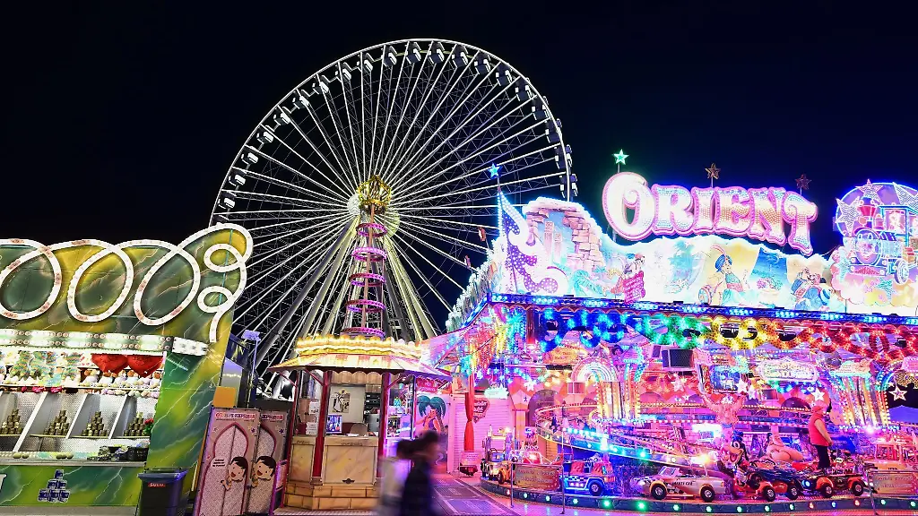 Fahrgeschaefte-auf-dem-Volksfest-Cannstatter-Wasen-sind-im-Abendlicht-in-Bewegung
