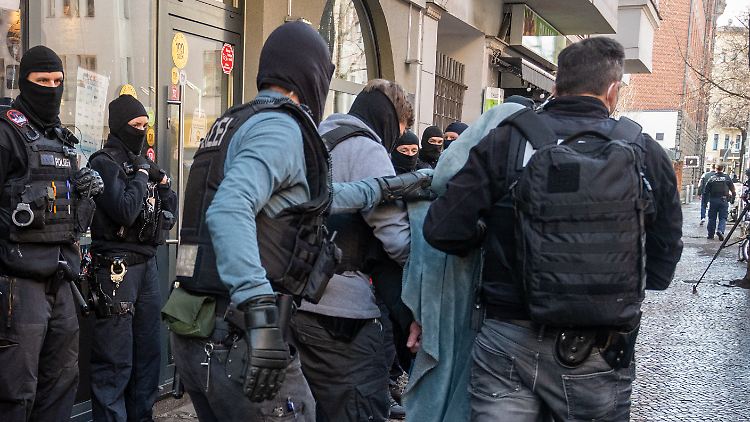Bei einer Großrazzia gegen Clankriminalität in Berlin und Umgebung im Februar wird unter anderem ein Mann mit einer Decke über dem Kopf von der Polizei abgeführt.