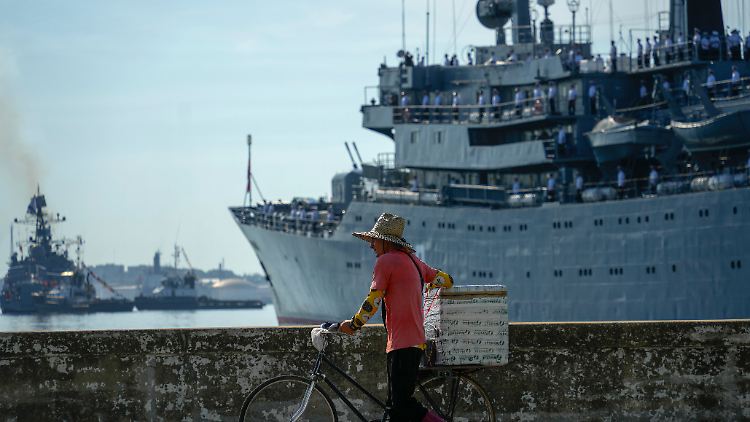 Ein Straßenverkäufer fährt mit seinem Fahrrad an dem russischen Übungsschiff "Smolny" vorbei, das in der Bucht von Havanna einläuft.