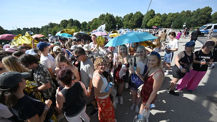 Viele Fans versuchten, sich vor dem Olympiapark mit Schirmen vor der Sonne zu schützen.
