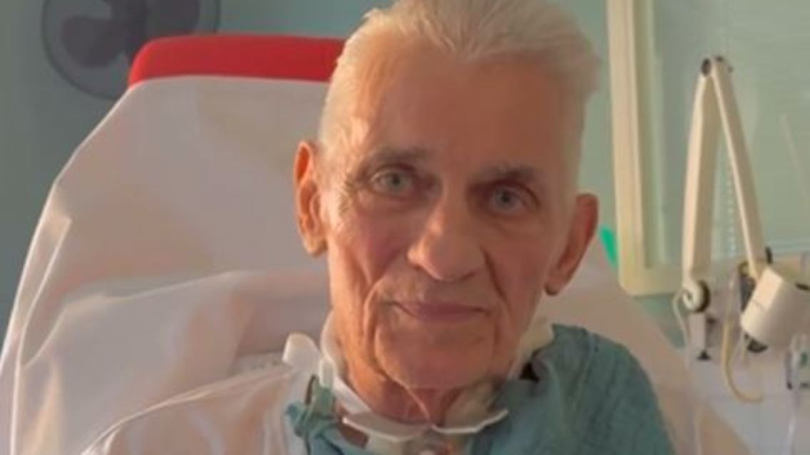 Während er in die Kamera spricht, sitzt Heinz Hoenig in einem Krankenhausbett, mit Tracheostoma am Hals, das ihm beim Atmen hilft. Der Schauspieler hat deutlich an Gewicht verloren.