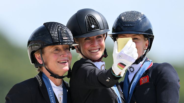 Zeit für ein Selfie mit der deutschen Goldmedaillengewinnerin Jessica von Bredow-Werndl (M), ihrer deutschen Kollegin Isabell Werth (l.), die Silber gewann, und Bronzegewinnerin Charlotte Fry aus Großbritannien. 