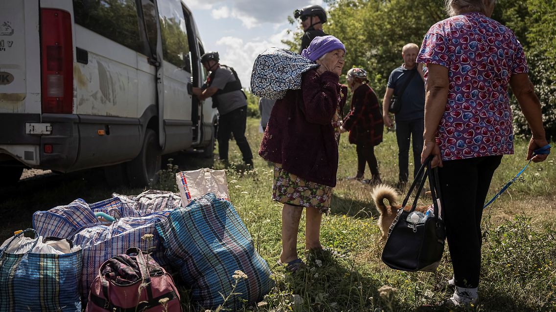 Bewohnerinnen eines Dorfes in der ukrainischen Grenzregion Sumy tragen ihr Gepäck zu einem Bus.