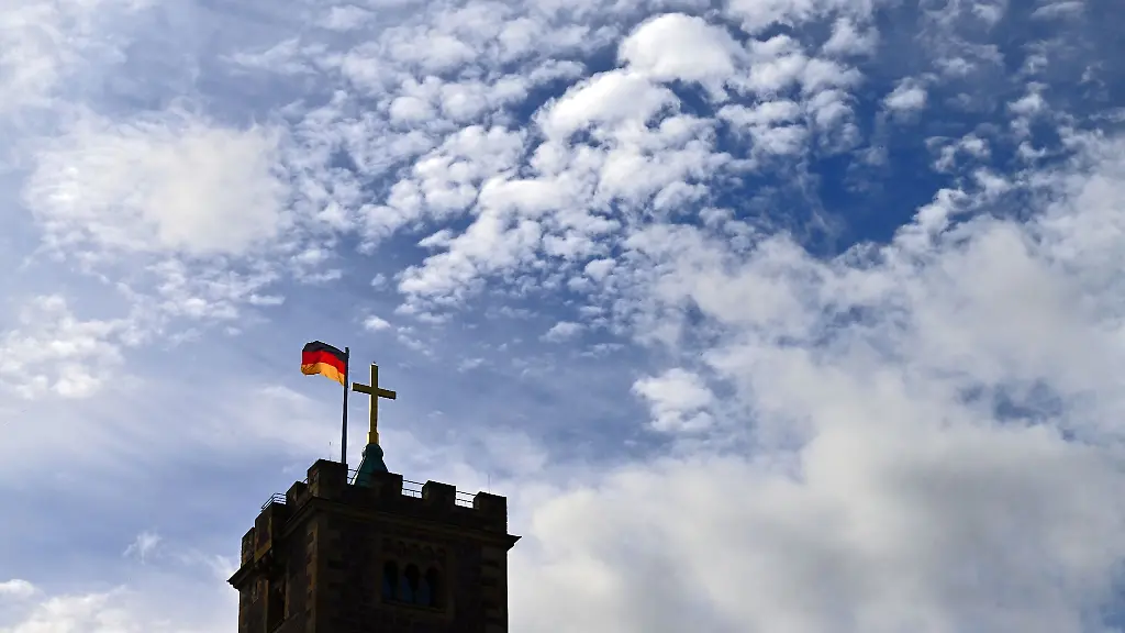 Wolken-ziehen-ueber-das-vergoldete-Turmkreuz-und-die-Deutschland-Fahne-auf-dem-Bergfried-der-Wartburg