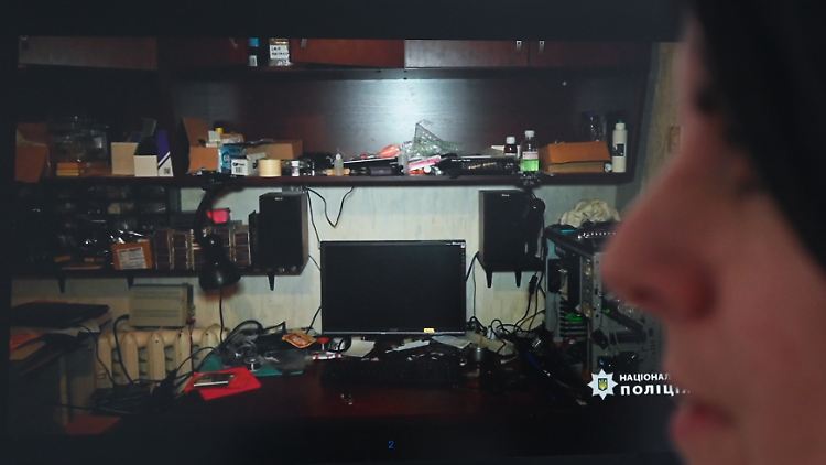Jana Ringwald sitzt in ihrem Büro vor einem Monitor, auf dem das Foto einer ausgehobenen Hackerwohnung zu sehen ist.