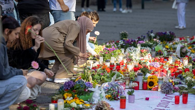 Menschen legen in der Nähe des Tatorts Blumen und Kerzen zum Gedenken der Opfer in Solingen nieder.
