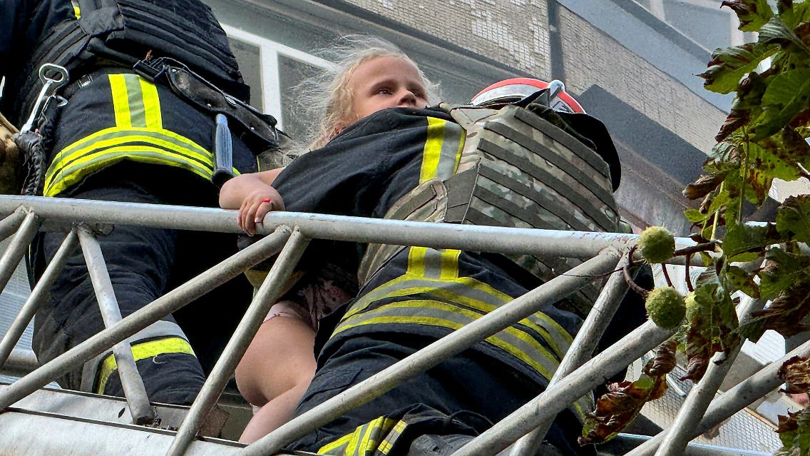 Feuerwehrleute retten ein Mädchen aus einem Wohnhaus in Charkiw, das von einer russischen Bombe getroffen wurde.