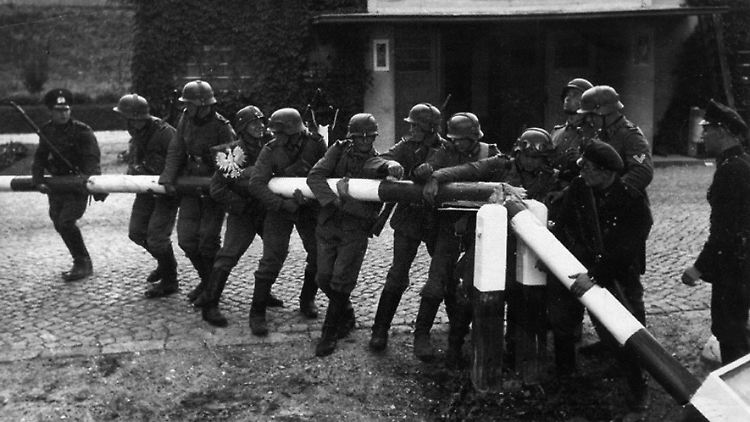 Soldaten der deutschen Wehrmacht reißen beim Einmarsch in Polen einen rot-weißen Schlagbaum an der deutsch-polnischen Grenze nieder.