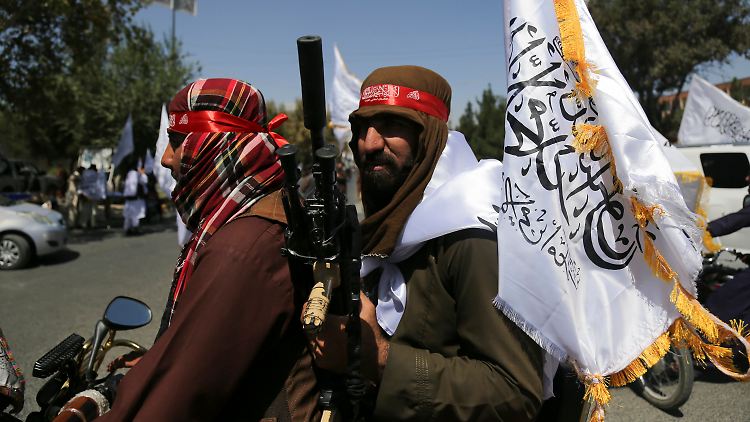 Taliban schwenken am zweiten Jahrestag ihrer Machtübernahme im August 2023 Fahnen in Kabul.