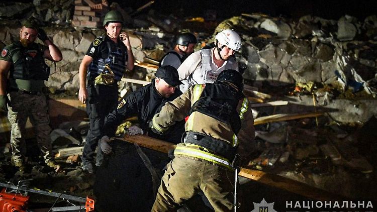 Rettungskräfte und Polizisten beseitigen Trümmer an einem Hotelgebäude in Saporischschja, das durch einen russischen Raketenangriff beschädigt wurde.