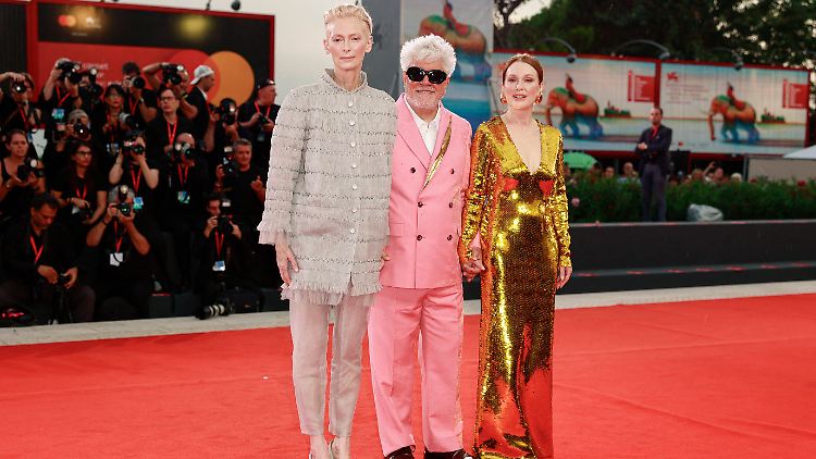 Tilda Swinton (l.) und Julianne Moore spielen die Hauptrollen in Pedro Almodóvars (M.) neuem Drama "The Room Next Door".
