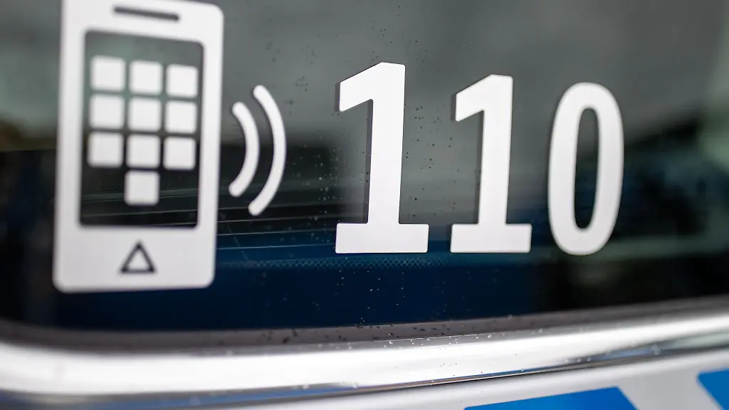 Der-Nummer-des-Polizeinotrufs-110-steht-auf-der-Scheibe-eines-Polizeifahrzeugs