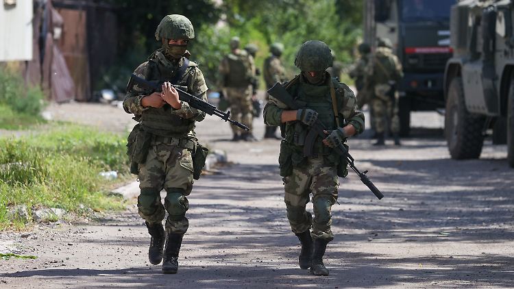 Russische Soldaten laufen im August 2022 durch das besetzte und zerstörte Mariupol in der Region Donezk.  
