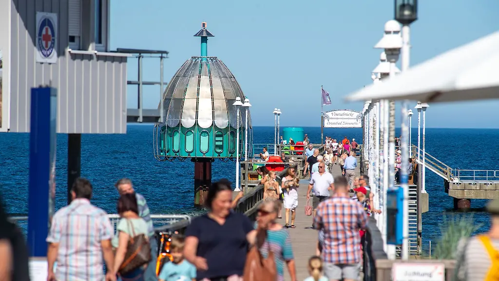 Touristen-laufen-bei-sonnigem-Wetter-ueber-der-Seebruecke