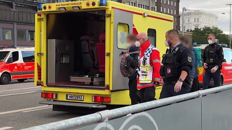 Einsatzkräfte begleiten zwei Menschen zu einem Spezialfahrzeug, das sie danach in die Klinik brachte. 