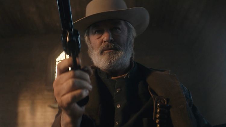 Alec Baldwin hält in einer Szene von "Rust" einen Revolver.