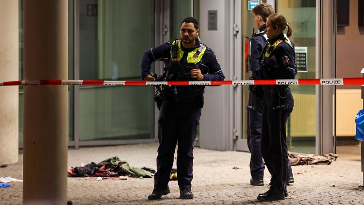 Polizisten stehen vor einem Kino, auf dem Boden liegt blutige Kleidung.