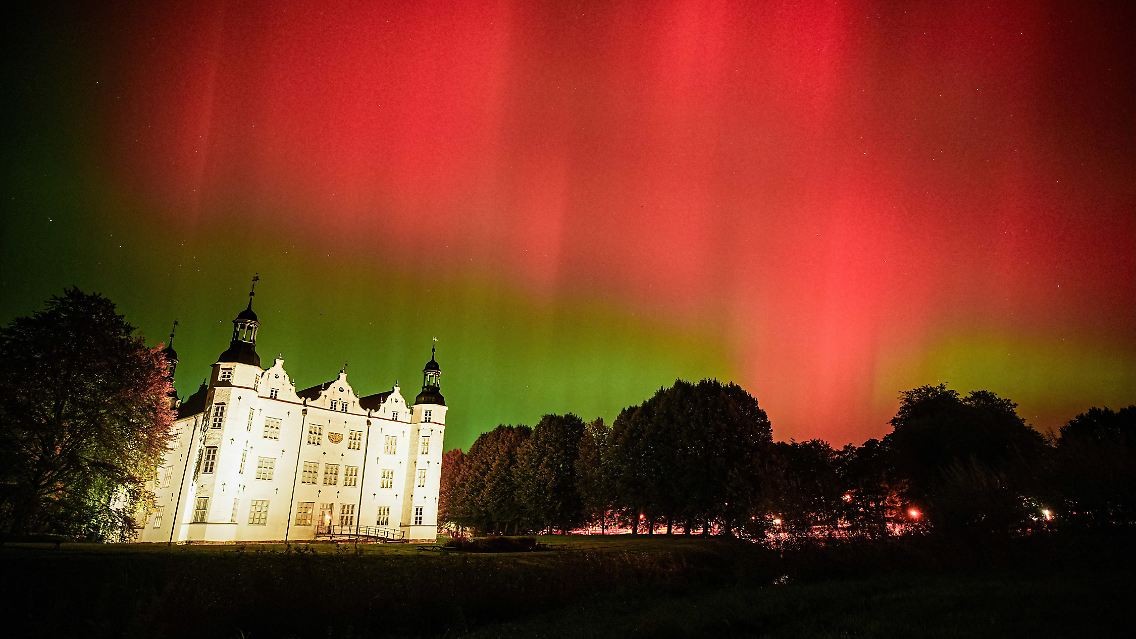 Polarlichter tanzen über dem Ahrensburger Schloss am Himmel.
