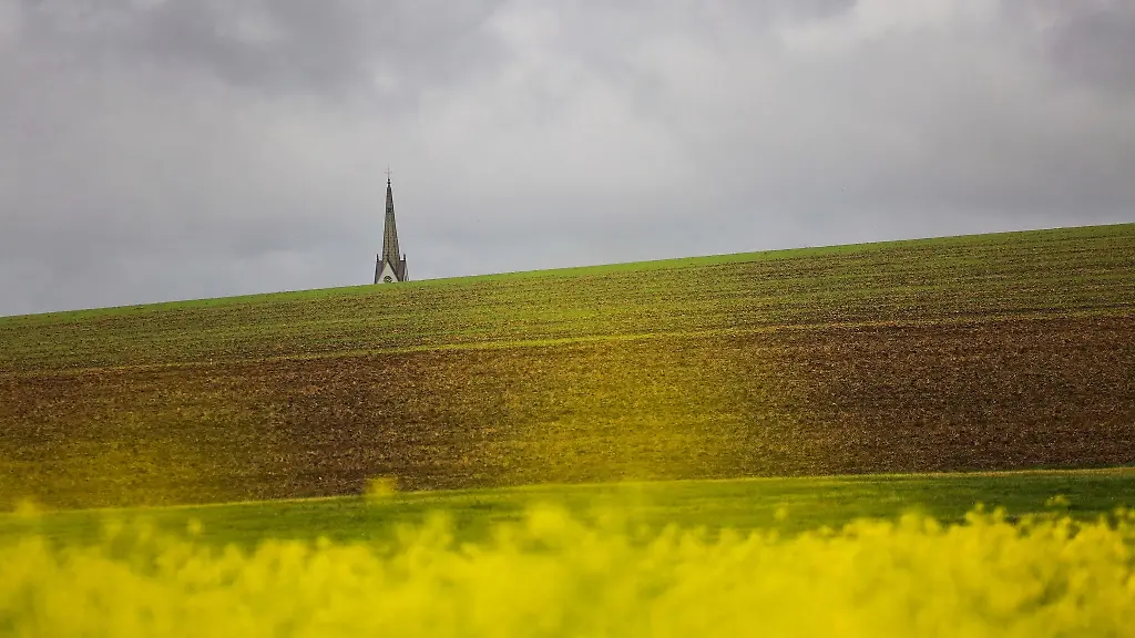 Hinter-dem-Kirchturm-der-Kirche-St-Petrus-ziehen-dunkle-Wolken-auf