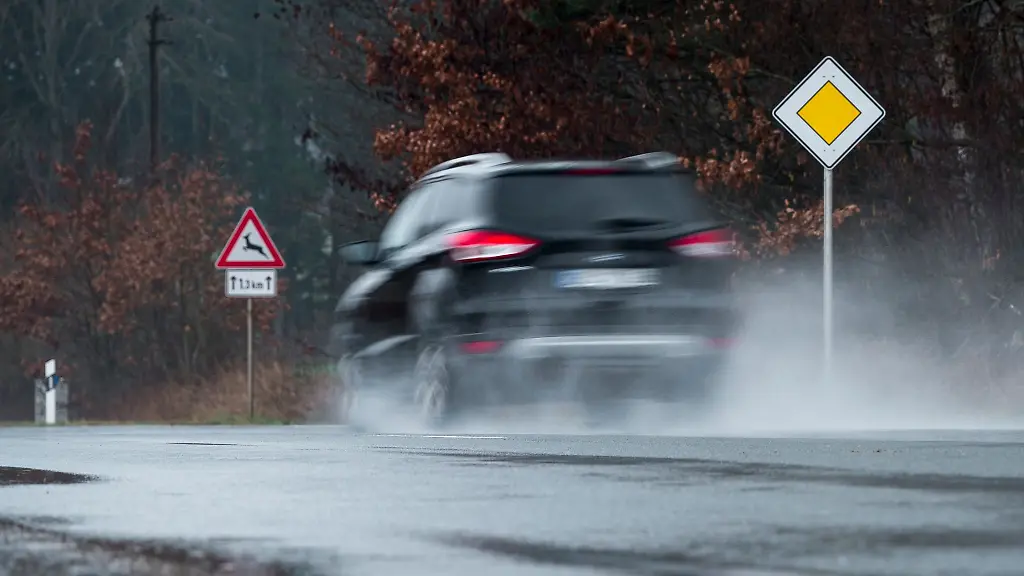 Ein-Auto-faehrt-bei-regnerischem-Wetter-ueber-eine-nasse-Strasse