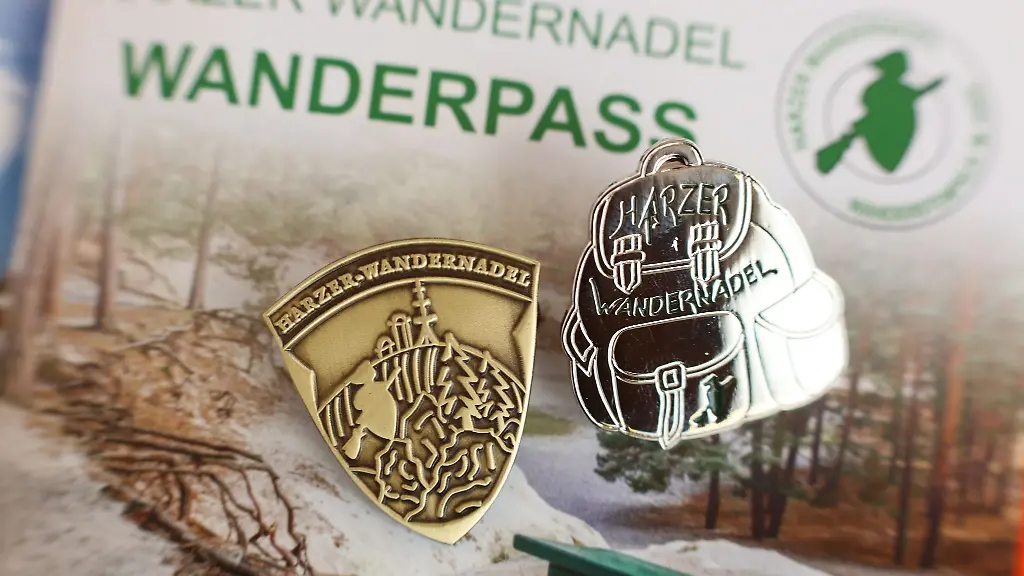 Abzeichen-der-Harzer-Wandernadel-liegen-auf-einem-Stempelheft