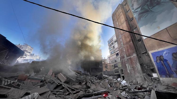 Rauch steigt nach einem israelischen Angriff in der Nähe eines Porträts des verstorbenen Hisbollah-Kommandeurs Imad Mugnijeh in dem Beiruter Vorort Dahieh auf.