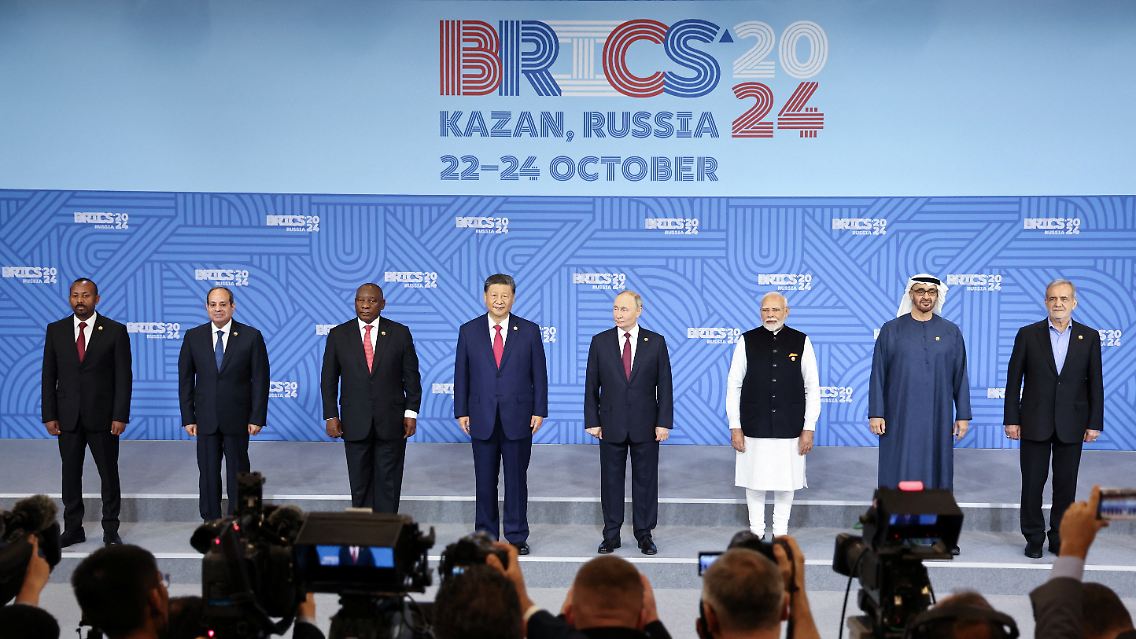 Kremlchef Putin wird eingerahmt von den Staats- und Regierungschefs von China, Indien, Äthiopien, Südafrika, Ägypten, den Vereinigten Arabischen Emiraten, des Iran, sowie von dem brasilianischen Außenminister.