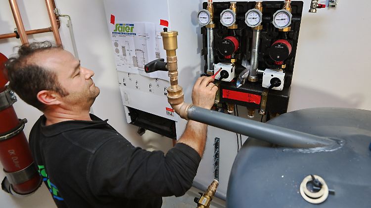 Ein Installateur bei der Einstellung einer Wärmepumpe. 
