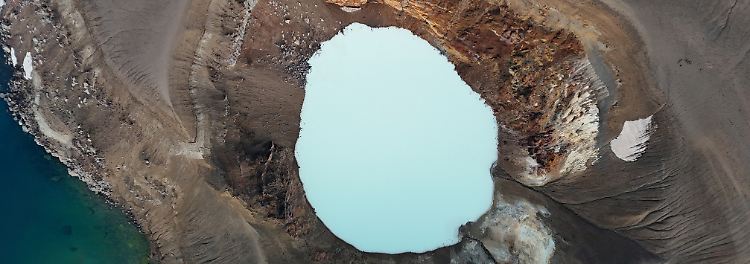 Das milchige, blassblaue Wasser im isländischen Viti-Krater blubbert und nach faulen Eiern stinkende Gase strömen an den steilen Wänden des vulkanischen Abgrunds nach oben.