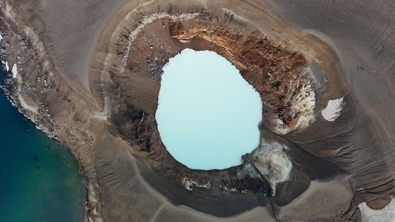 Das milchige, blassblaue Wasser im isländischen Viti-Krater blubbert und nach faulen Eiern stinkende Gase strömen an den steilen Wänden des vulkanischen Abgrunds nach oben.