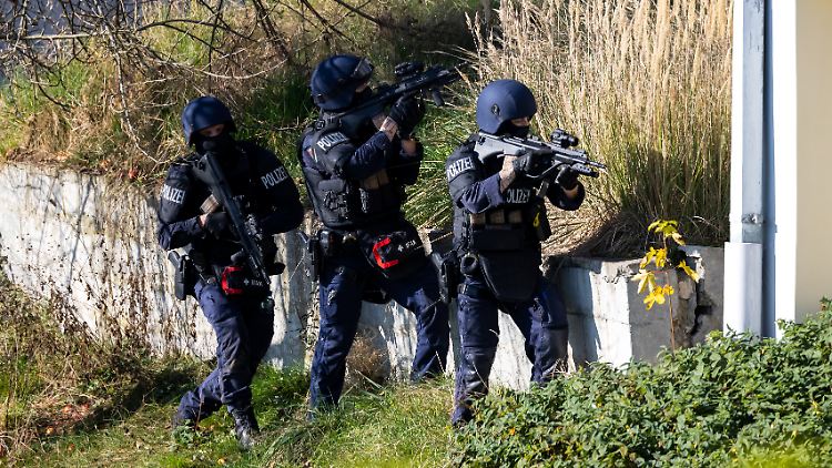 Polizisten durchsuchen die Gegend um das gefundene Auto herum nach dem Flüchtigen.