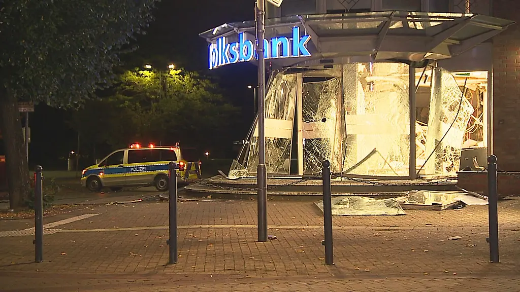 Ein-Polizeiauto-steht-vor-einem-gesprengten-Geldautomaten-im-Vorraum-einer-Bank-in-Alpen