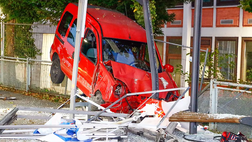 Ein-Auto-steckt-am-Unfallort-in-einem-Wartehaeuschen-einer-Bushaltestelle