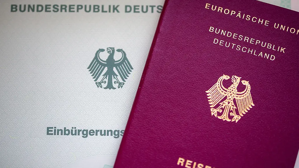 Eine-Einbuergerungsurkunde-und-ein-deutscher-Reisepass-liegen-auf-einem-Tisch