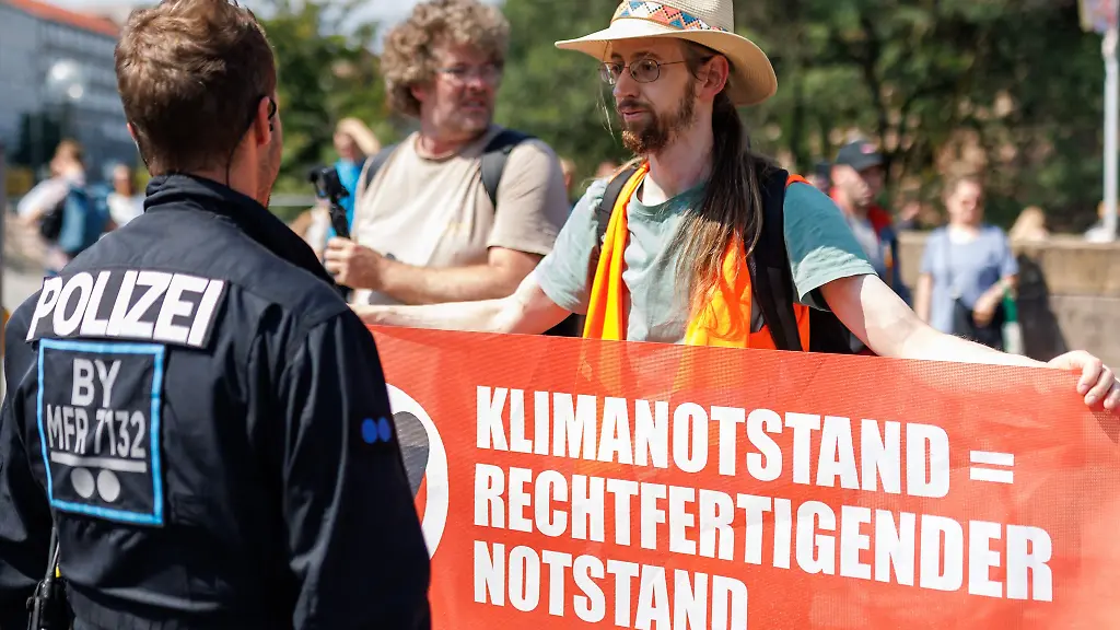 Ein-Aktivist-r-der-Klimaschutzorganisation-Letzte-Generation-protestiert-vor-dem-Nuernberger-Hauptbahnhof