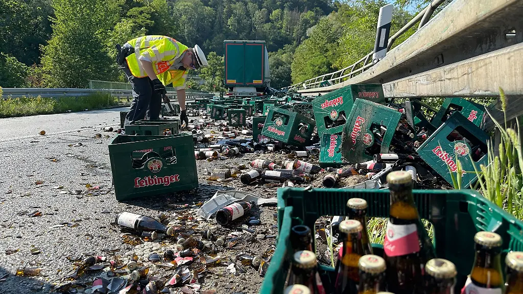 Ein-Polizist-ist-an-der-Unfallstelle-an-der-ein-Lastwagen-bei-einem-Unfall-ueber-100-Kisten-Bier-verloren-hat