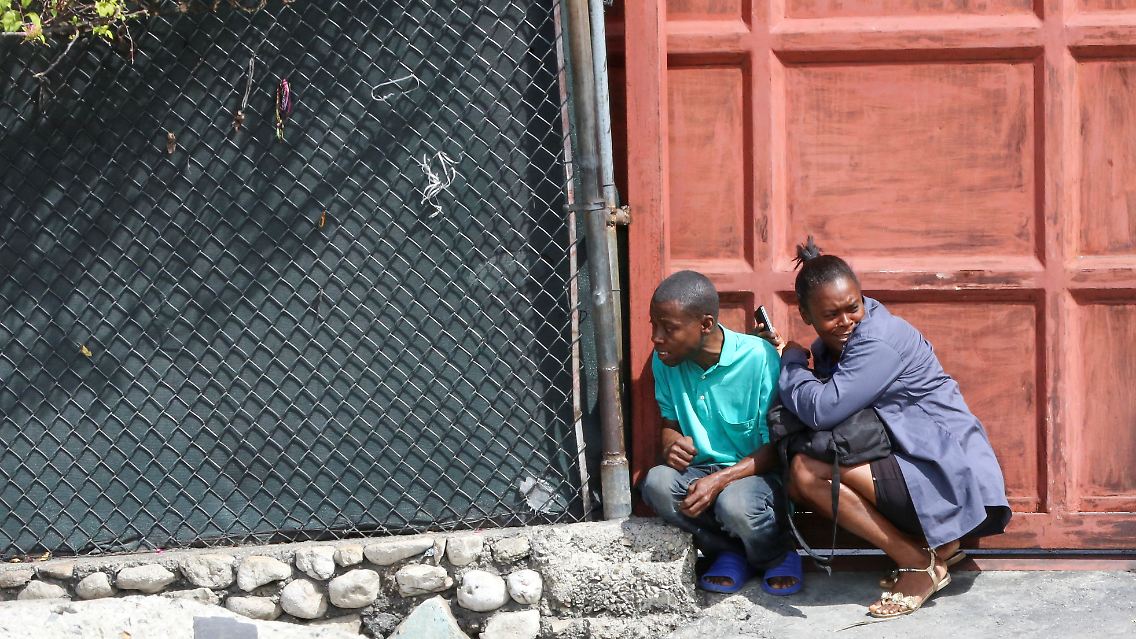 In Port-au-Prince gehen zwei Menschen in Deckung, als es zu Zusammenstößen zwischen Gangs und Sicherheitskräften kommt.