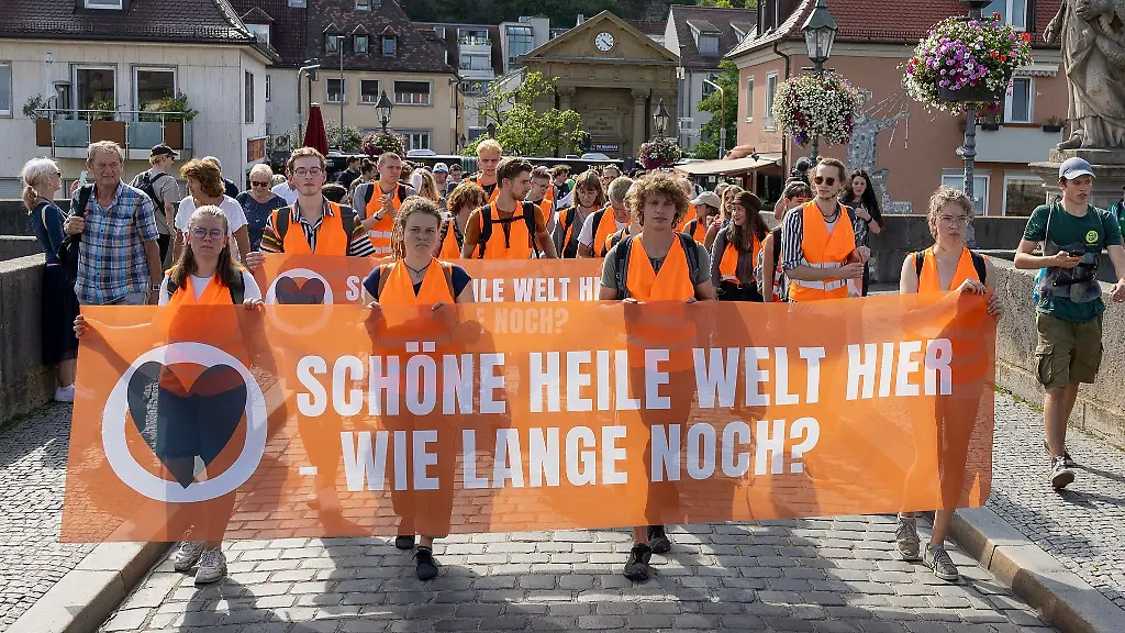 Anhaenger-der-Letzten-Generation-ziehen-in-einem-Protestmarsch-durch-Wuerzburg